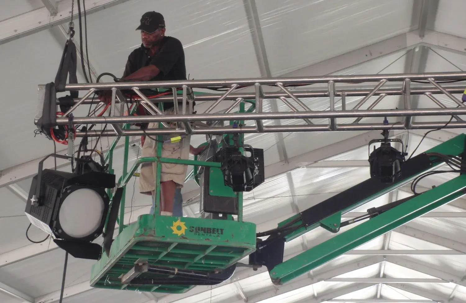 Technician on lift adjusting stage lighting equipment.