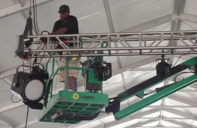 Technician on lift adjusting stage lighting equipment.