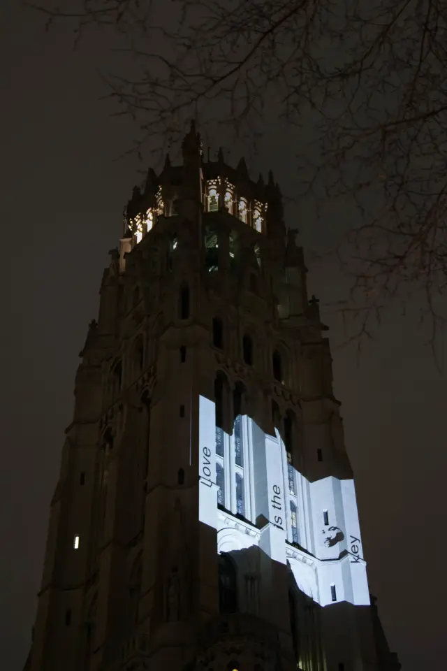 Gothic-style tower with illuminated projection reading 'Love is the key' at night.