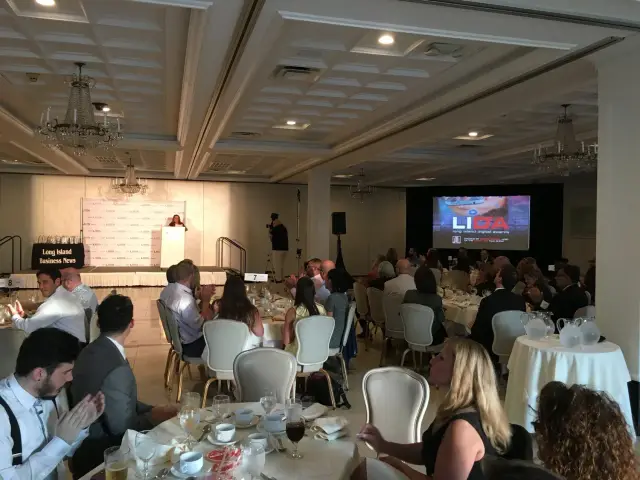 Banquet hall with people seated at tables, a speaker at a podium, projection screen displaying 'Long Island Digital Awards,' and Long Island Business News signage.