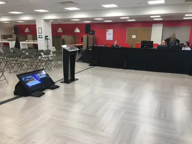 Empty conference room with podium, chairs, and screens.